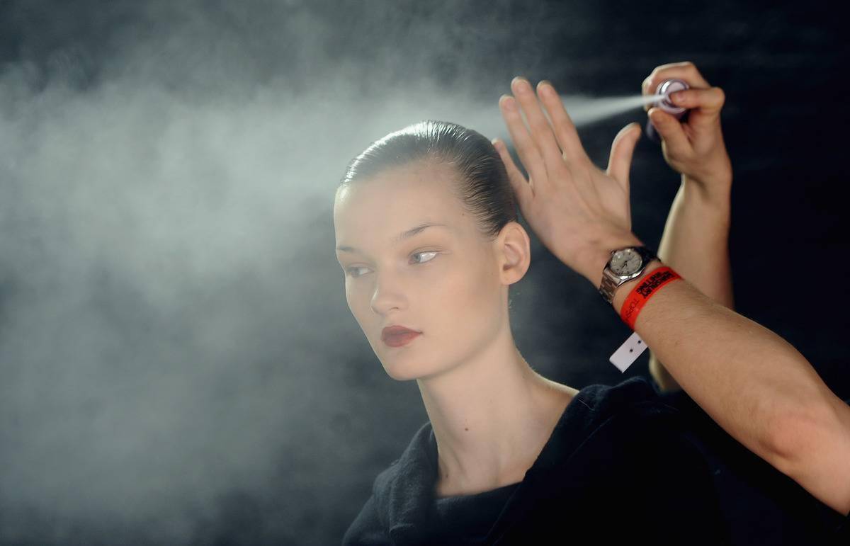 A person sprays hair spray on a model.