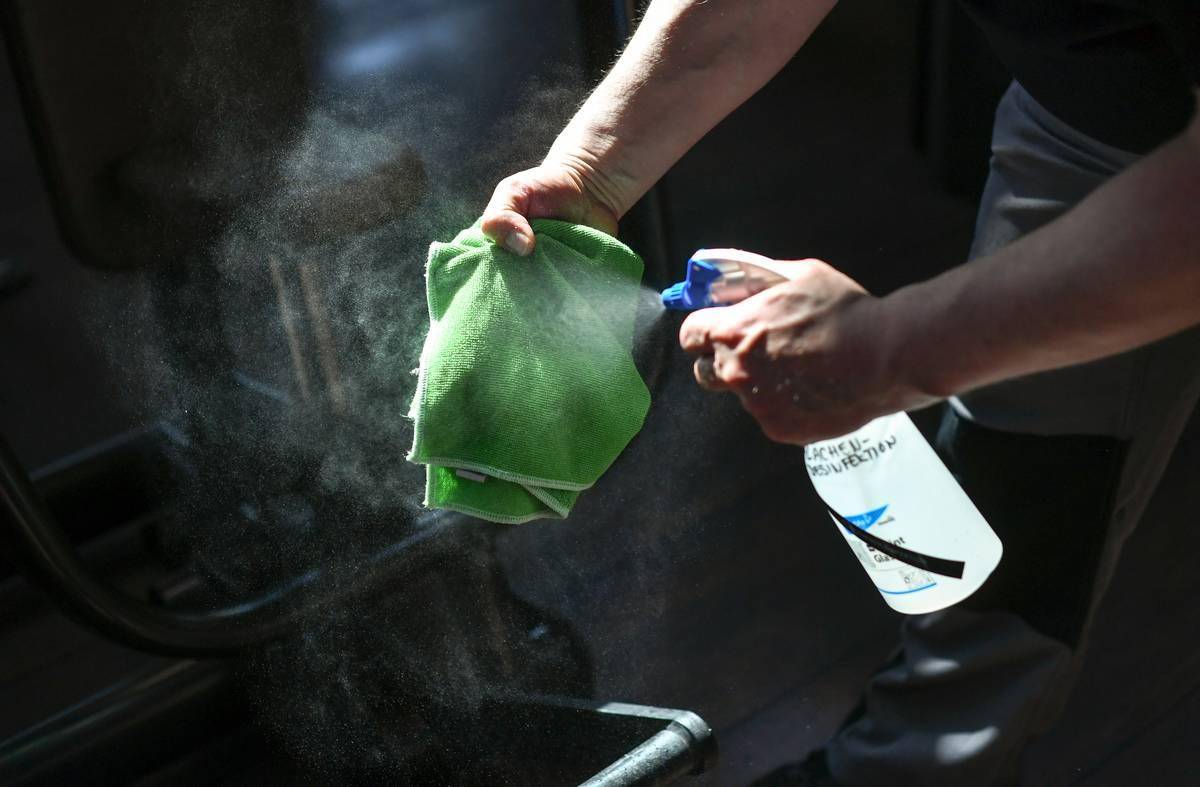 A person sprays a towel with a disinfectant.