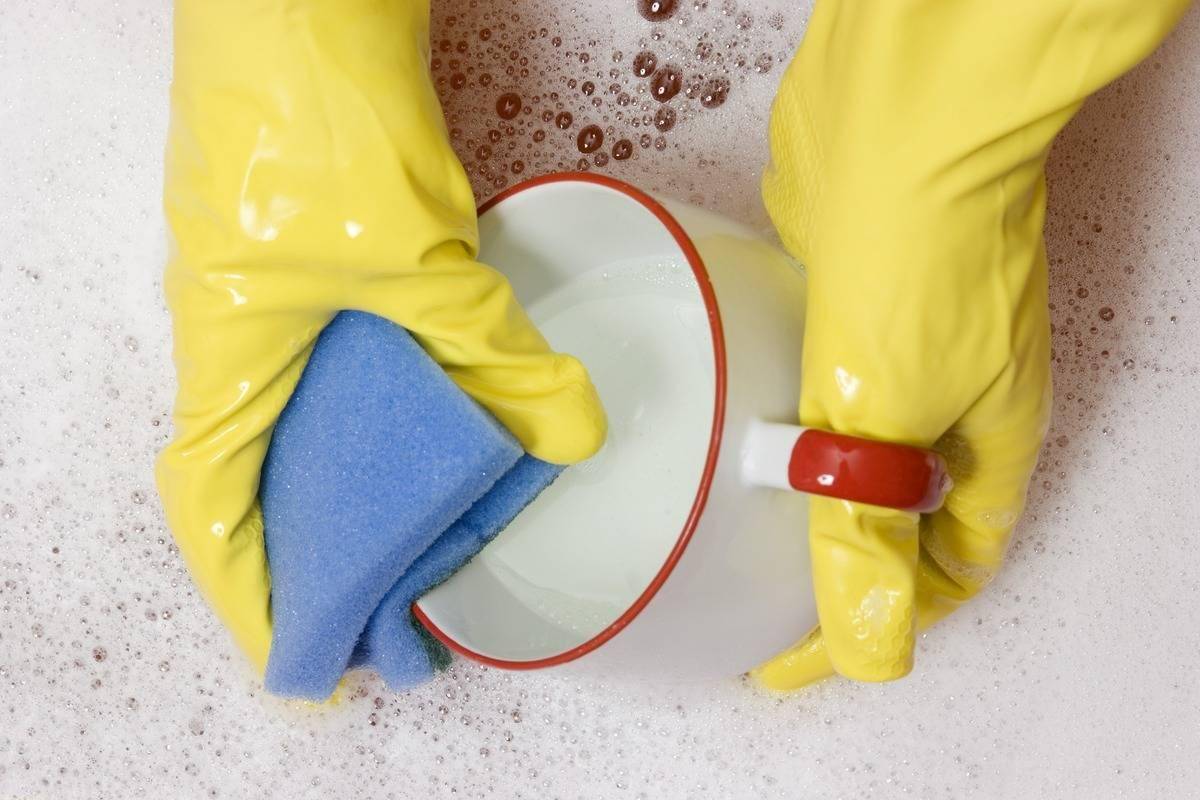 A person washes a mug with a sponge.