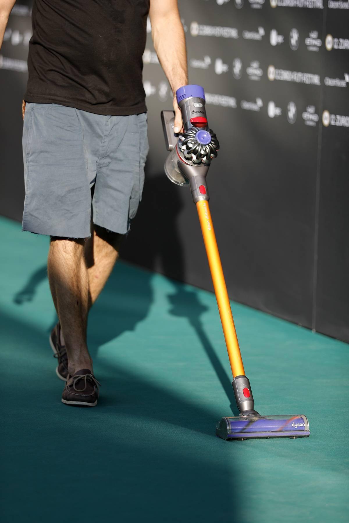 An employee vacuums a green carpet.