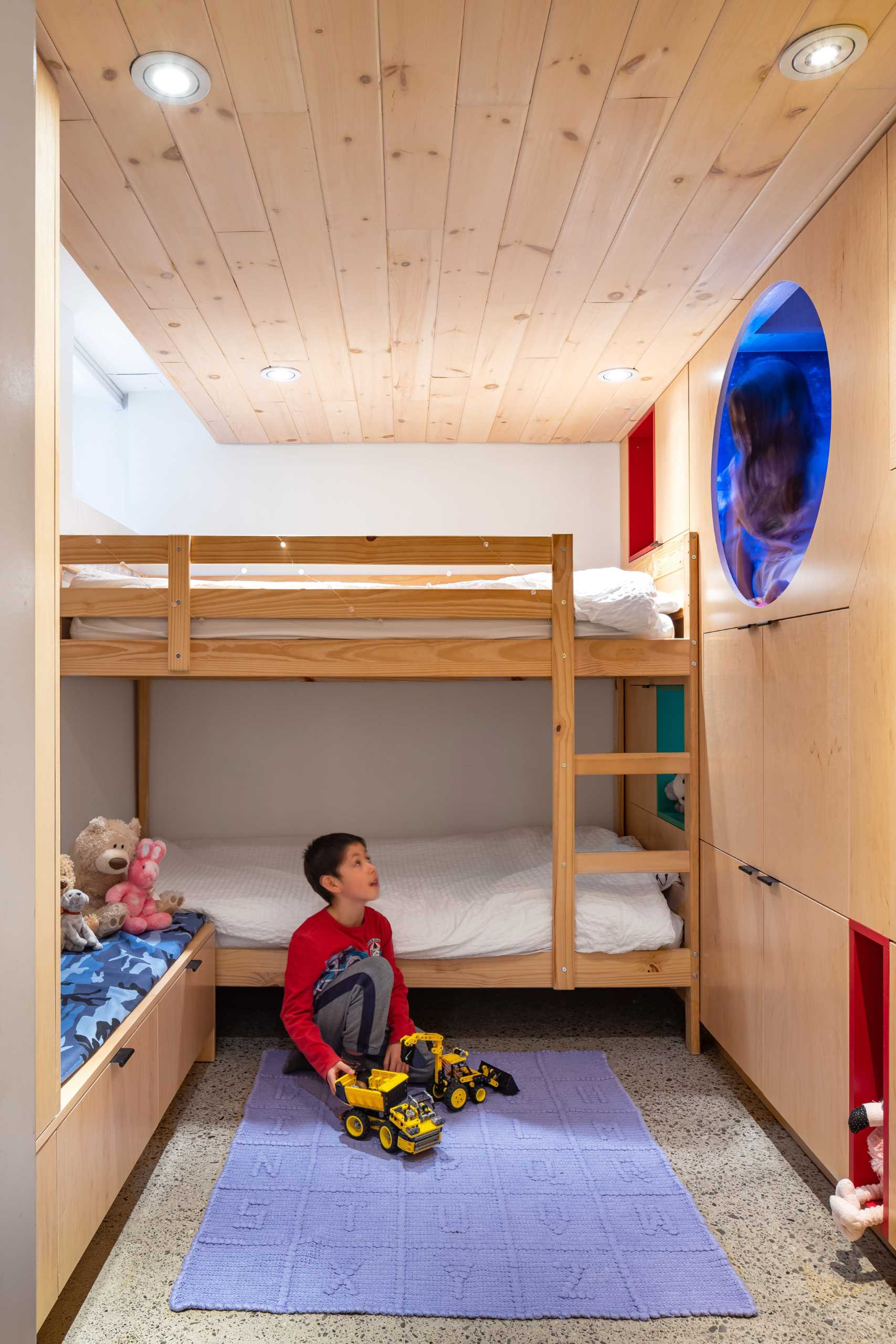 A kids bedroom with built-in storage in the form of cabinets and benches, as well as bunk beds, and two reading nooks.