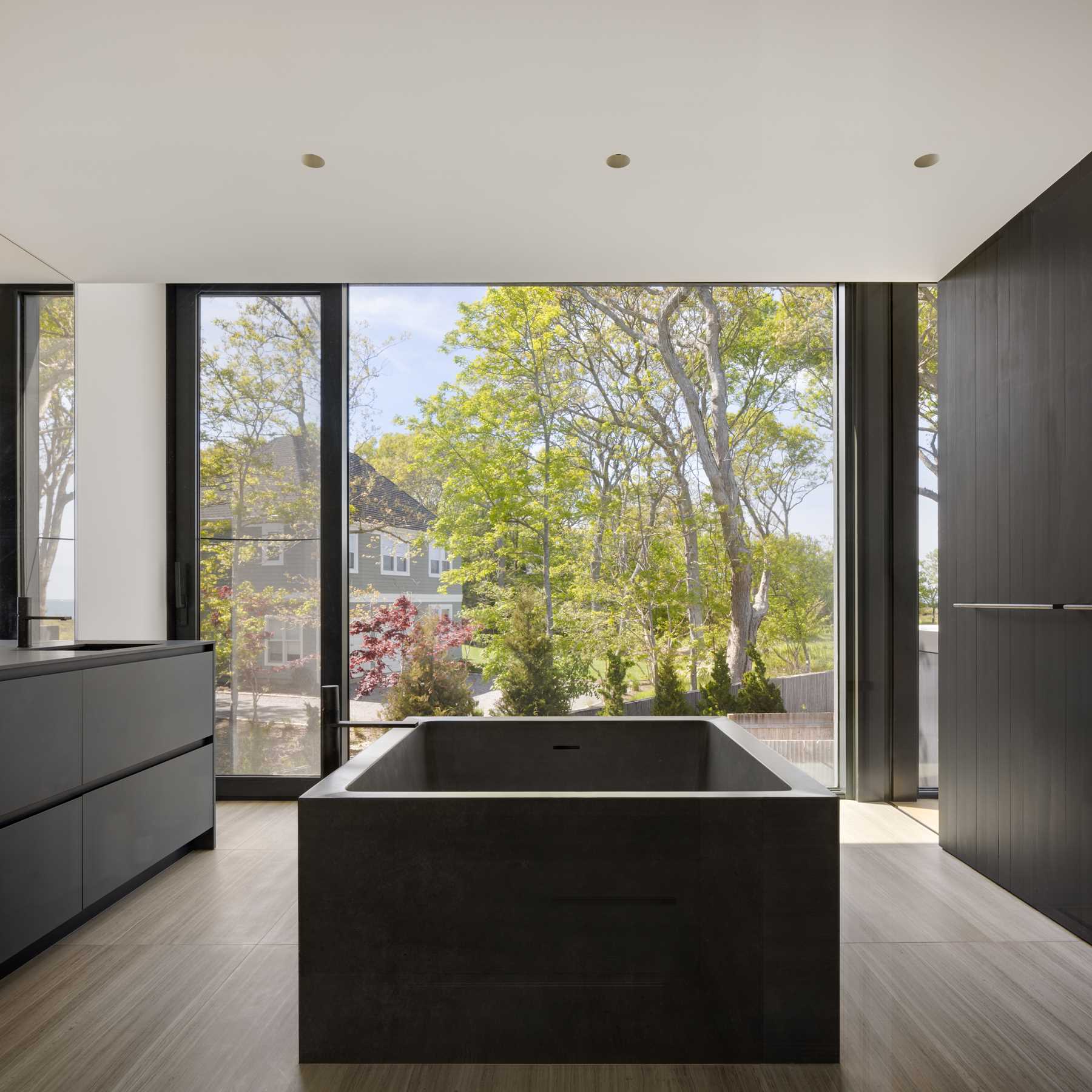 In the bathroom, a sculptural, custom concrete floating tub is placed in the center of the bathroom, while a steam shower is available behind.