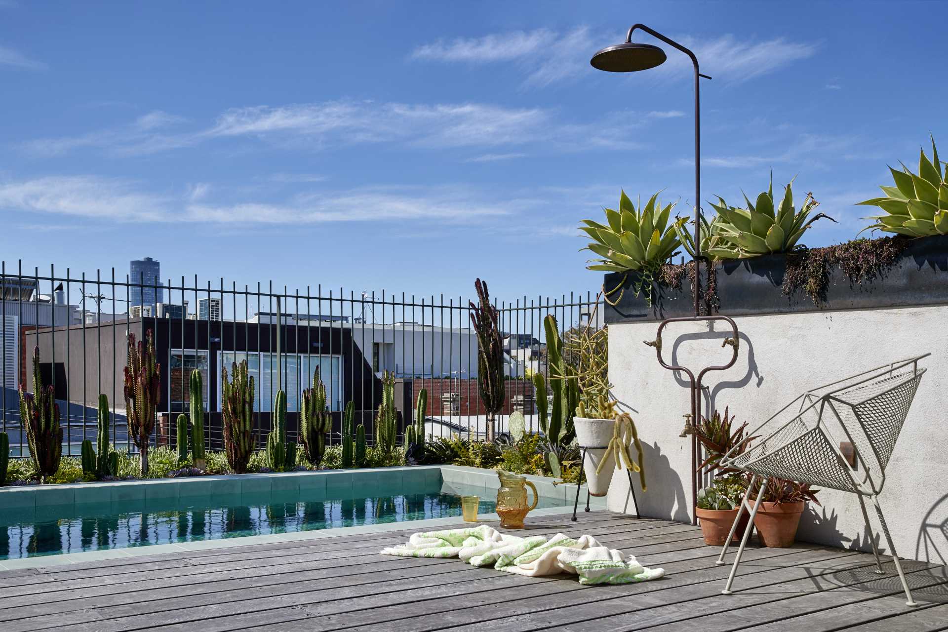 A rooftop terrace lined with steel-topped planter boxes, also includes a small pool and outdoor shower.