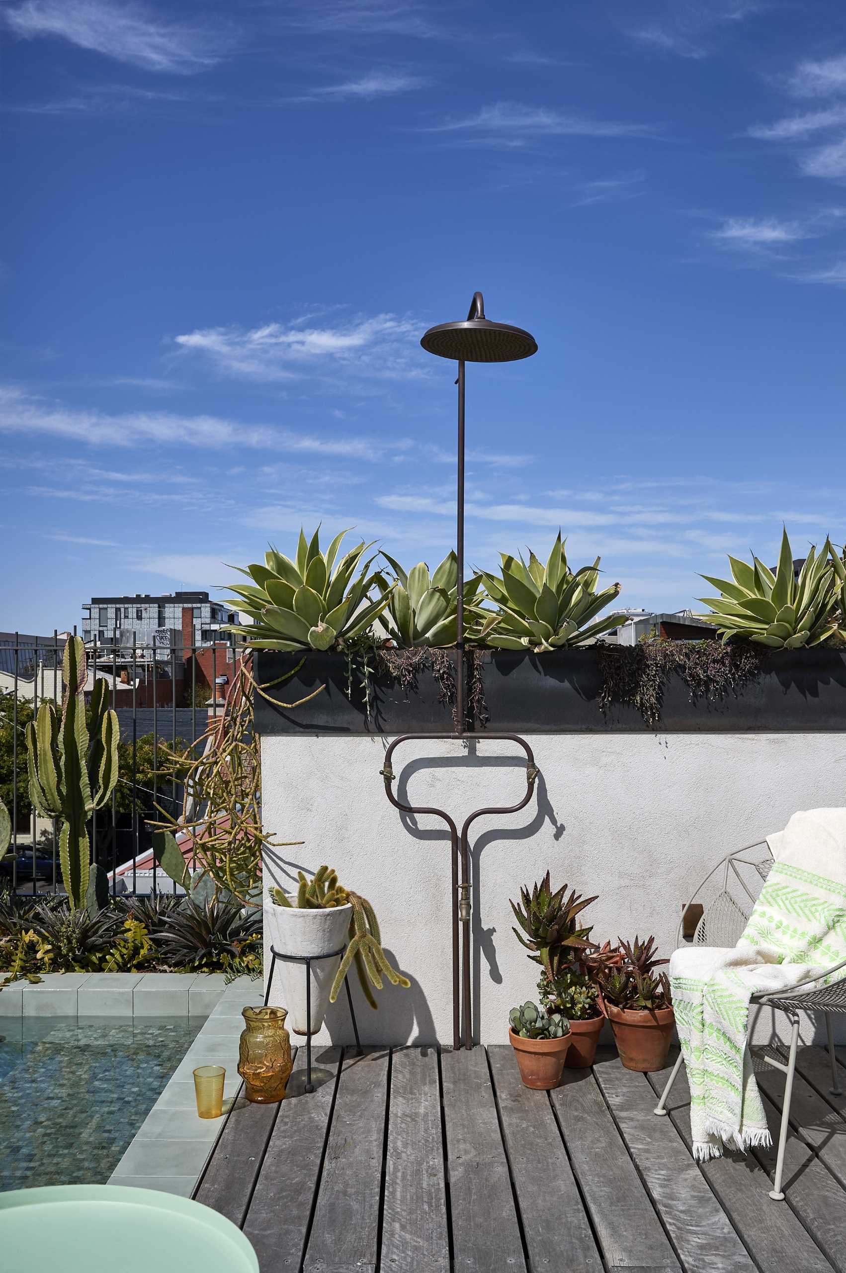 A rooftop terrace lined with steel-topped planter boxes, also includes a small pool and outdoor shower.