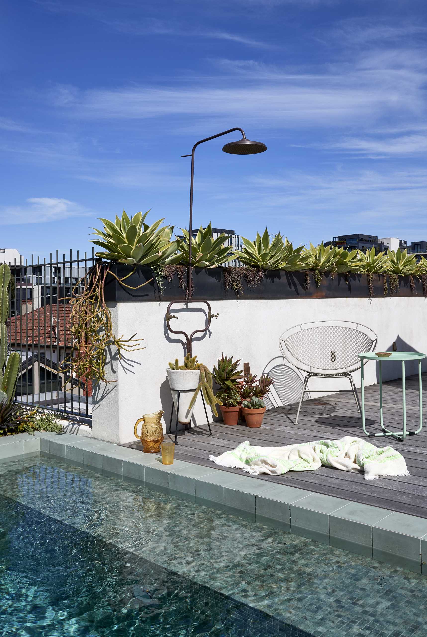 A rooftop terrace lined with steel-topped planter boxes, also includes a small pool and outdoor shower.