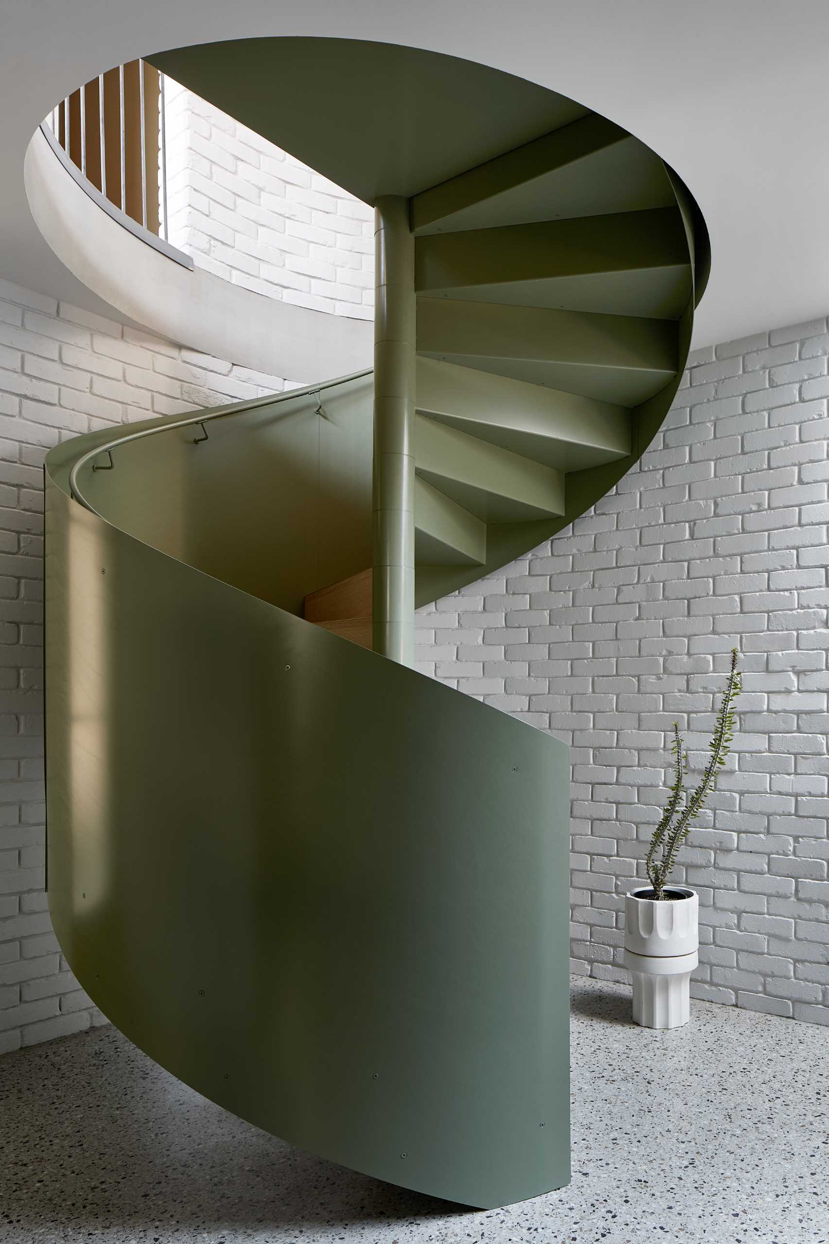 A green spiral staircase travels from the entry level to the main social areas of the home.