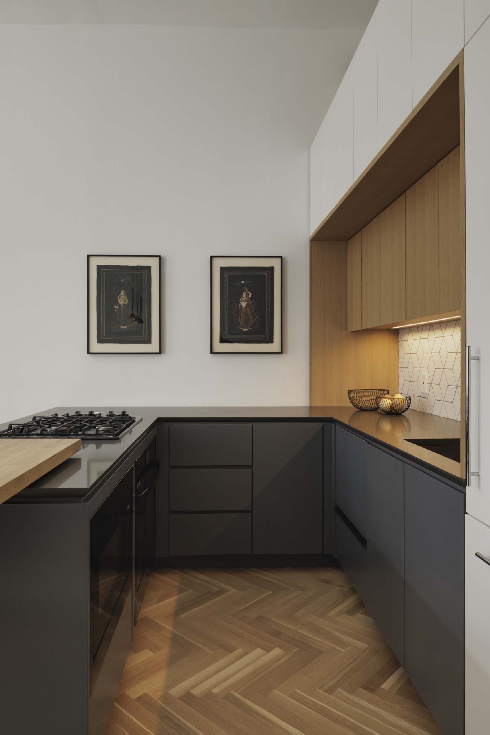 A modern kitchen with dark grey and wood cabinets.