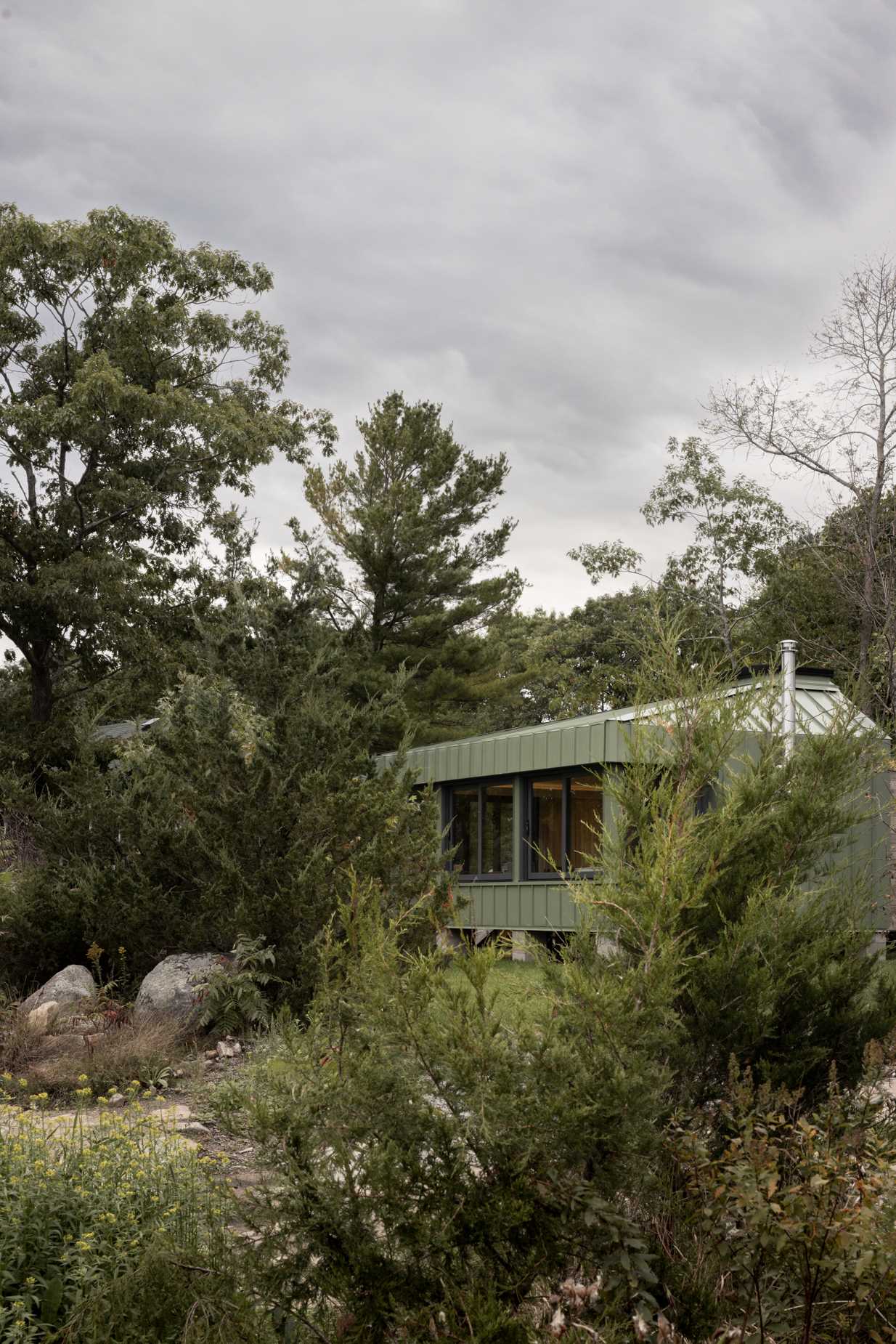 A modern cabin clad in sage green standing seam metal siding.