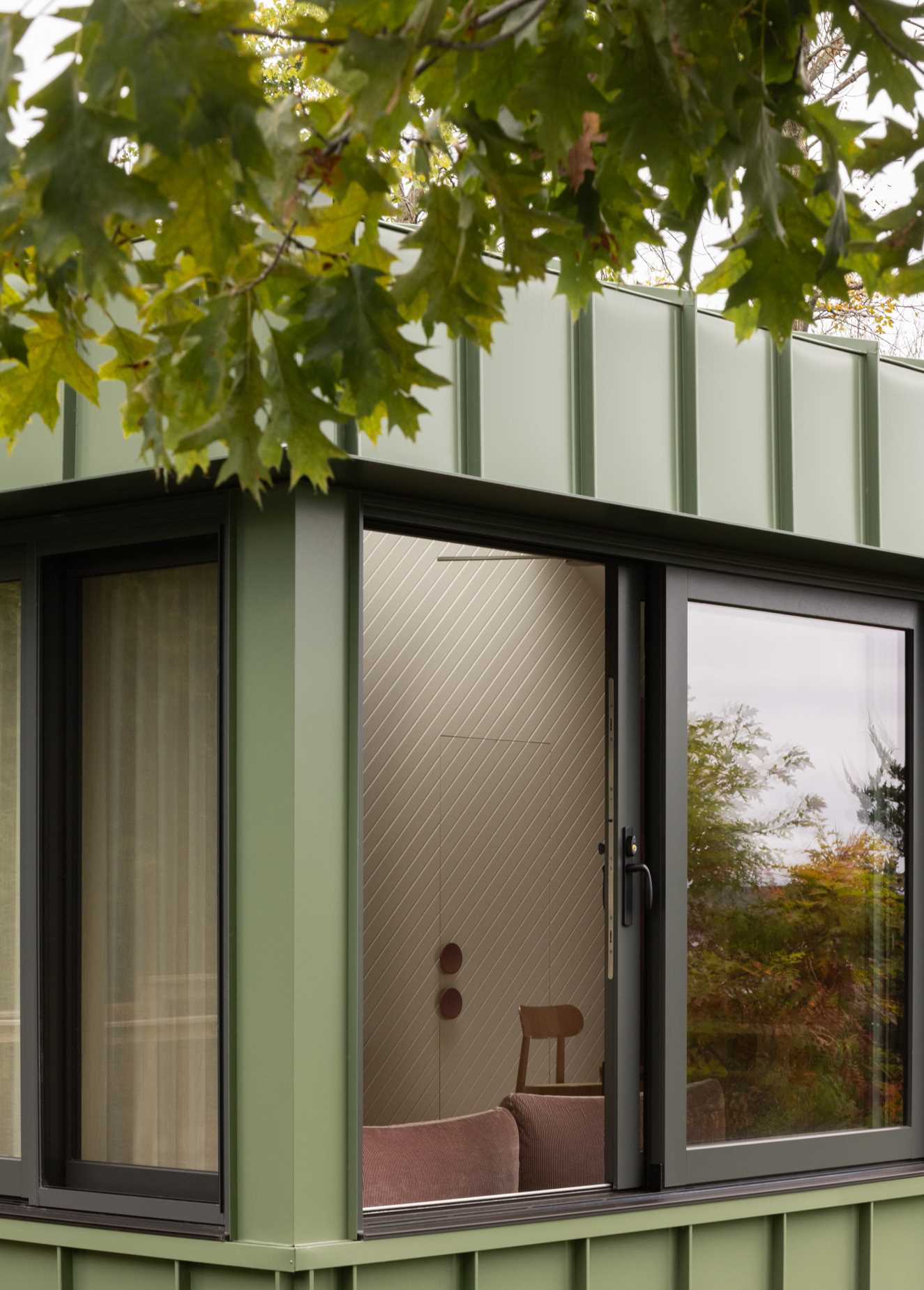 A modern cabin clad in sage green standing seam metal siding.