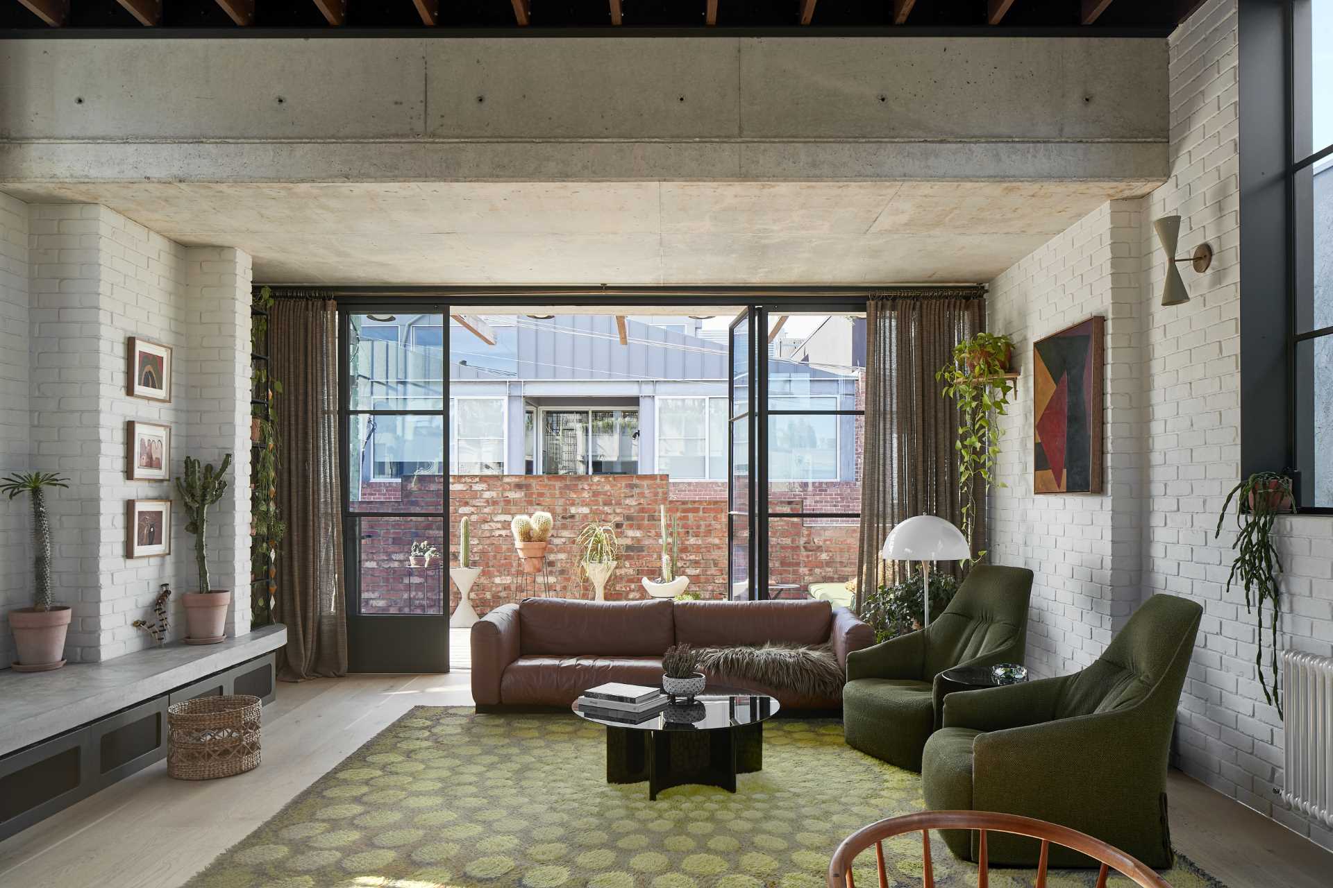 The social area of this warehouse-inspired home, with its 13 foot (4m) ceiling height and steel windows, is filled with an abundance of light coming in through the east, north and west facades.