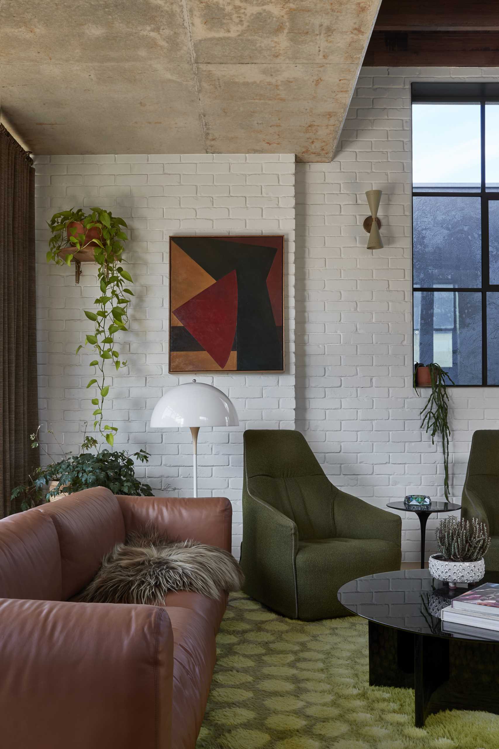 In the living room, exposed concrete has been paired with white-painted brick and a black steel fireplace.