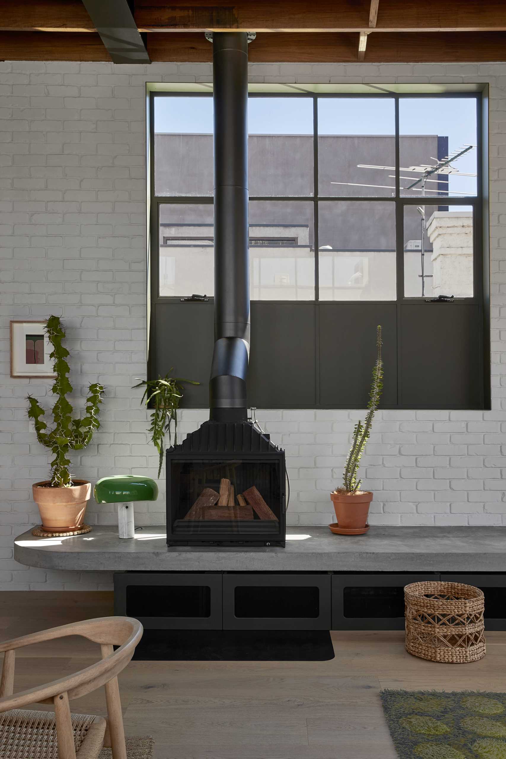 In the living room, exposed concrete has been paired with white-painted brick and a black steel fireplace.